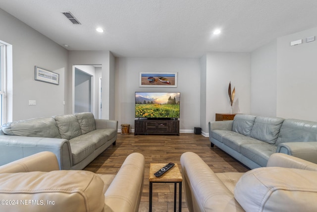 living room featuring dark wood-type flooring and a textured ceiling