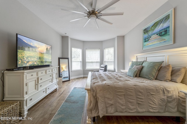 bedroom featuring light hardwood / wood-style flooring, ceiling fan, and a textured ceiling