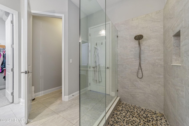 bathroom with a tile shower and tile patterned flooring