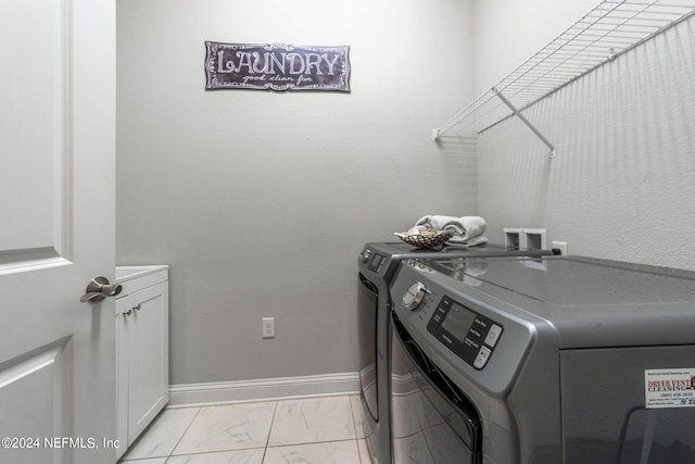 laundry area with independent washer and dryer and cabinets