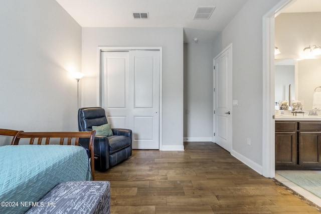 bedroom with a closet, dark hardwood / wood-style floors, and ensuite bath