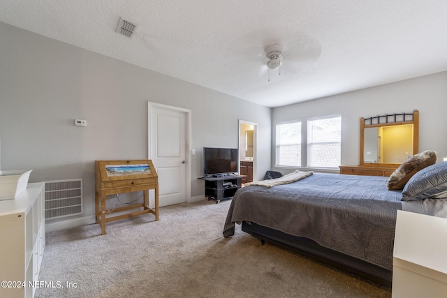 carpeted bedroom with a textured ceiling, ensuite bathroom, and ceiling fan