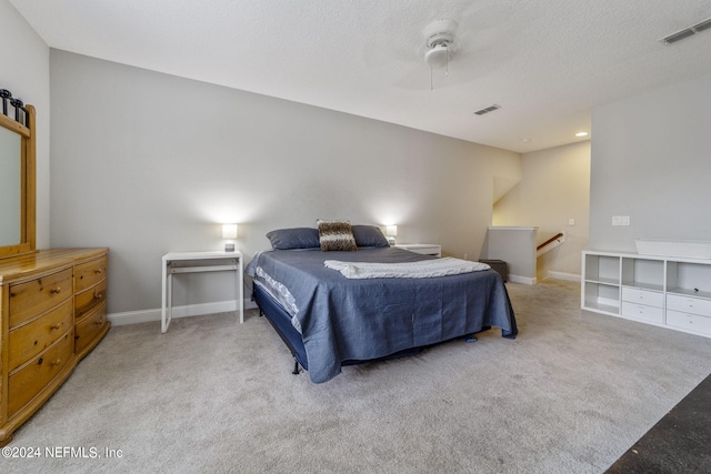 bedroom with ceiling fan, a textured ceiling, and light colored carpet