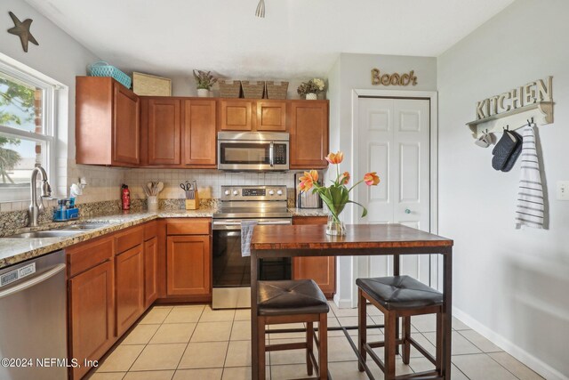 kitchen featuring backsplash, sink, appliances with stainless steel finishes, and light tile patterned floors