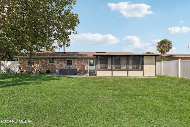 back of house featuring a sunroom and a lawn