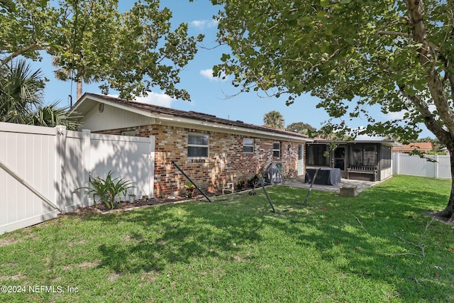 rear view of house with a sunroom and a yard