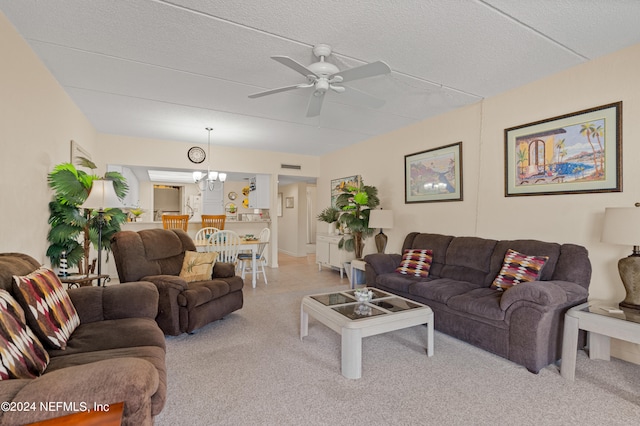 living room featuring light carpet, ceiling fan with notable chandelier, and a textured ceiling