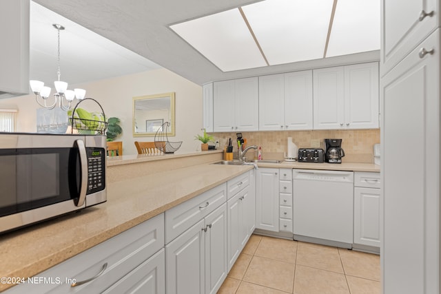 kitchen with an inviting chandelier, hanging light fixtures, white dishwasher, white cabinets, and light tile patterned flooring