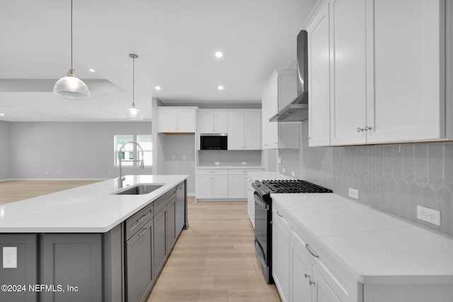 kitchen with wall chimney exhaust hood, appliances with stainless steel finishes, sink, and white cabinets