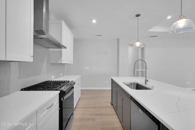 kitchen with white cabinetry, stainless steel appliances, hanging light fixtures, and wall chimney range hood