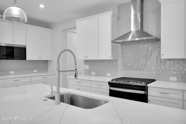 kitchen featuring white cabinets, stainless steel appliances, hanging light fixtures, and wall chimney exhaust hood