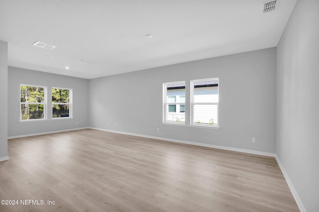 empty room with light hardwood / wood-style floors and a textured ceiling