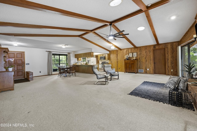 living room with light carpet, lofted ceiling with beams, wooden walls, ceiling fan, and a textured ceiling