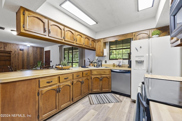 kitchen with dishwasher, a textured ceiling, a healthy amount of sunlight, and sink