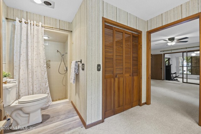 bathroom with toilet, walk in shower, and ceiling fan