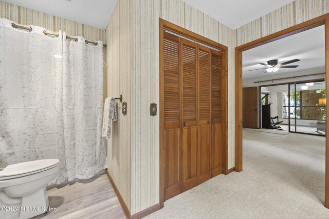 bathroom with a textured ceiling, toilet, and ceiling fan