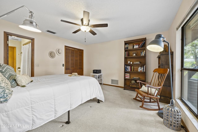 carpeted bedroom with ceiling fan, a textured ceiling, and a closet