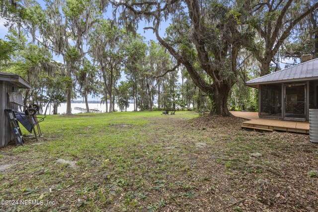 view of yard with a sunroom and a water view