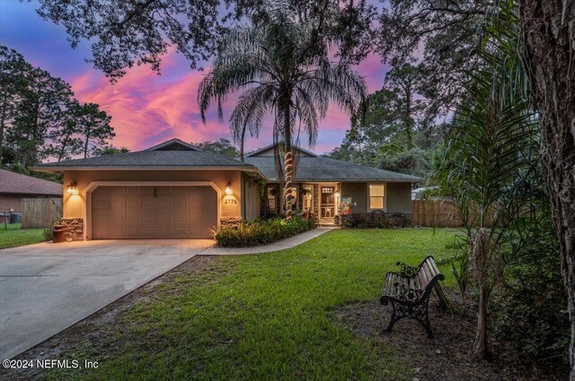 ranch-style home featuring a garage and a lawn