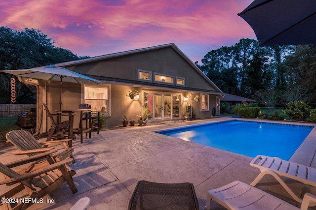 pool at dusk with a patio area