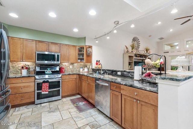 kitchen featuring dark stone countertops, sink, stainless steel appliances, and kitchen peninsula