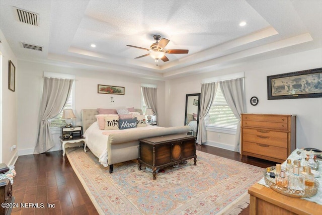 bedroom featuring a raised ceiling, dark hardwood / wood-style floors, and a textured ceiling