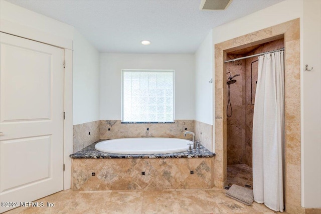 bathroom with shower with separate bathtub and a textured ceiling