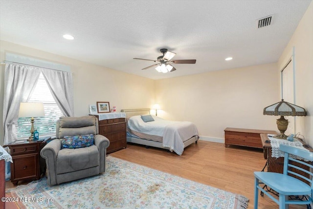 bedroom featuring ceiling fan, a textured ceiling, and light wood-type flooring