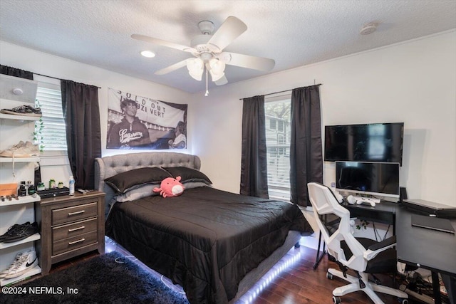 bedroom featuring dark hardwood / wood-style flooring, ceiling fan, and a textured ceiling