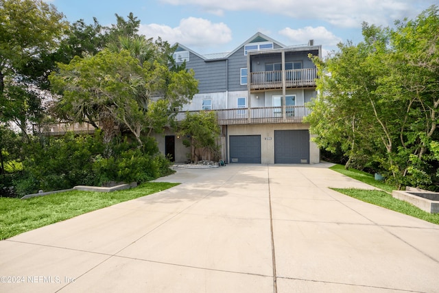 view of front of property with concrete driveway, an attached garage, a balcony, and stucco siding