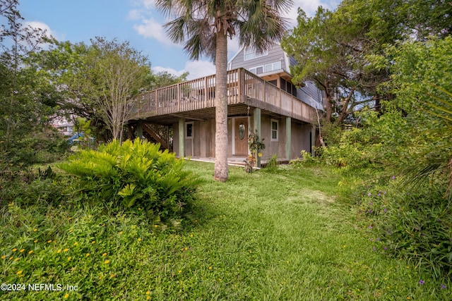 back of property with a deck and a yard