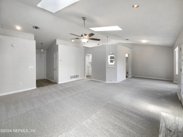 unfurnished living room featuring lofted ceiling with skylight, light carpet, and ceiling fan