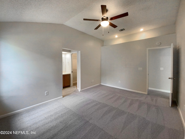 carpeted empty room with a textured ceiling, vaulted ceiling, and ceiling fan