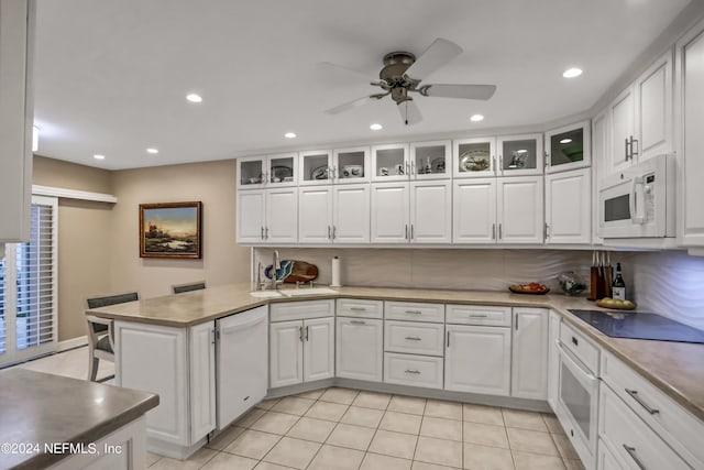 kitchen with glass insert cabinets, white cabinetry, a sink, white appliances, and a peninsula