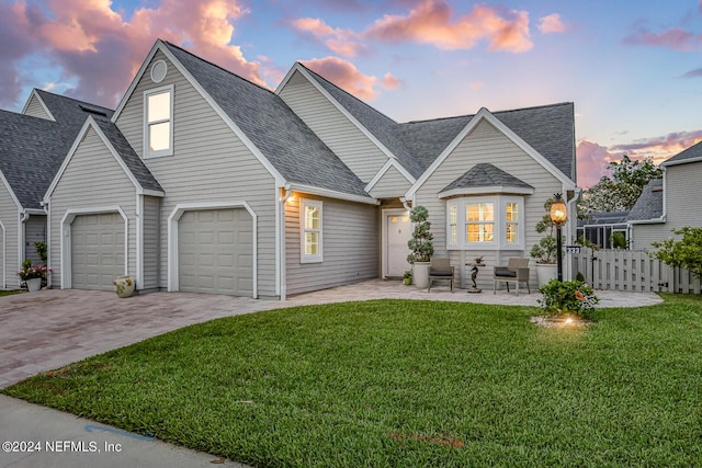 view of front of property with driveway, a shingled roof, fence, and a lawn