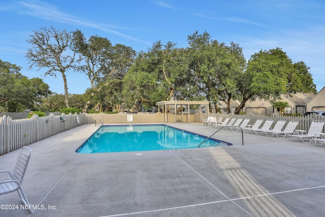 pool with a patio area, fence, and a pergola