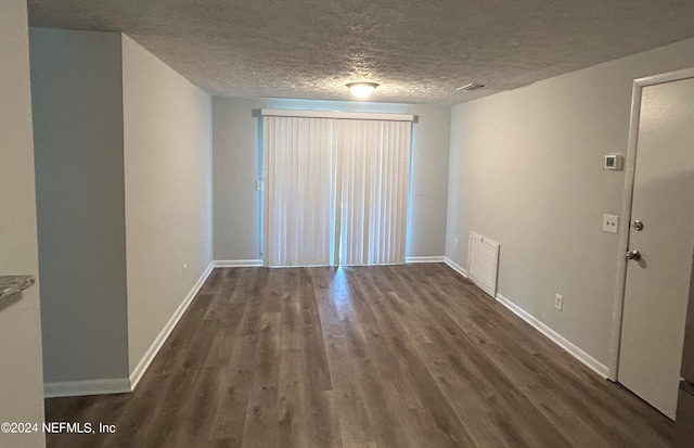 unfurnished room featuring a textured ceiling and dark hardwood / wood-style floors