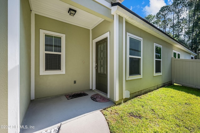 entrance to property featuring a lawn and a patio