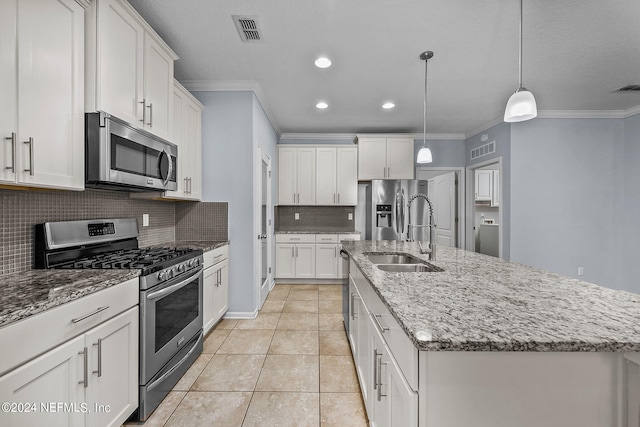 kitchen featuring appliances with stainless steel finishes, decorative light fixtures, white cabinetry, ornamental molding, and a kitchen island with sink