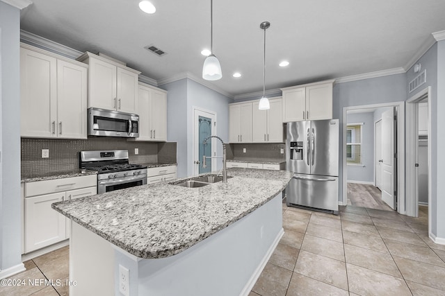 kitchen featuring appliances with stainless steel finishes, pendant lighting, white cabinetry, sink, and a center island with sink