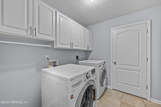 laundry area with washer and dryer, light tile patterned floors, cabinets, and a textured ceiling