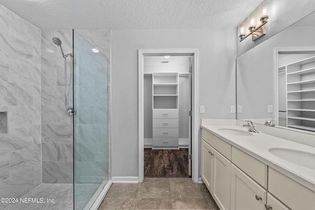 bathroom with vanity, a tile shower, and a textured ceiling