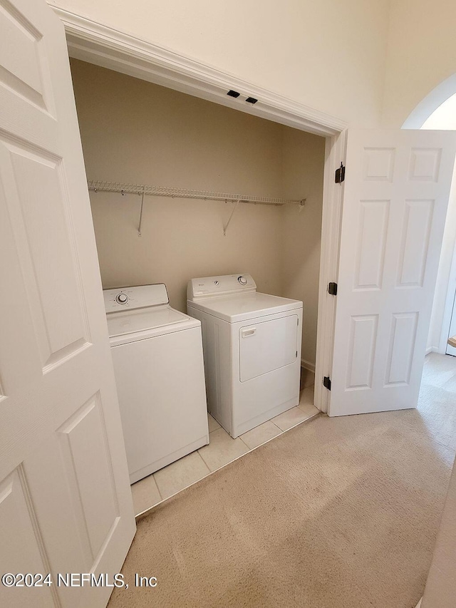 clothes washing area featuring light tile patterned floors and independent washer and dryer