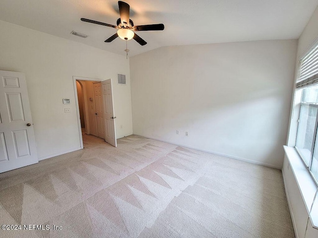 spare room featuring lofted ceiling, light colored carpet, and ceiling fan