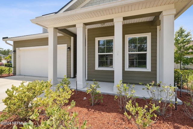 doorway to property with a garage and a porch