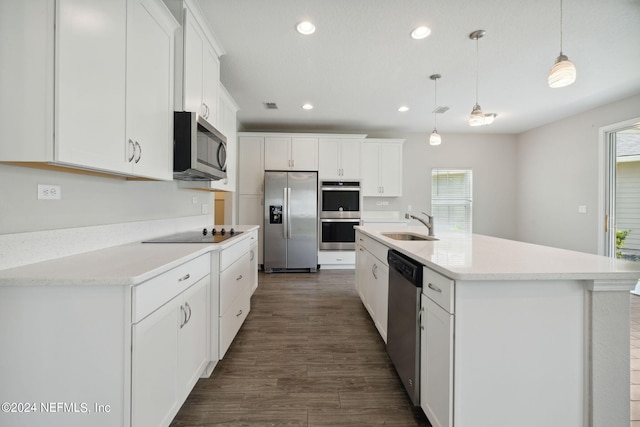 kitchen featuring white cabinetry, decorative light fixtures, a center island with sink, and appliances with stainless steel finishes