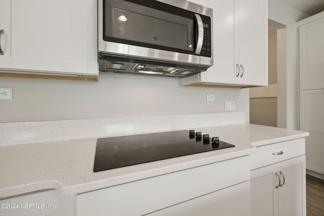 kitchen featuring white cabinetry, black electric cooktop, light stone countertops, and wood-type flooring