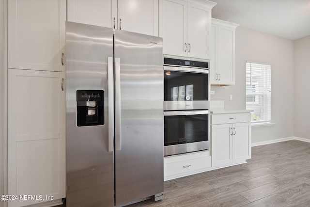 kitchen with white cabinetry, light hardwood / wood-style floors, and appliances with stainless steel finishes