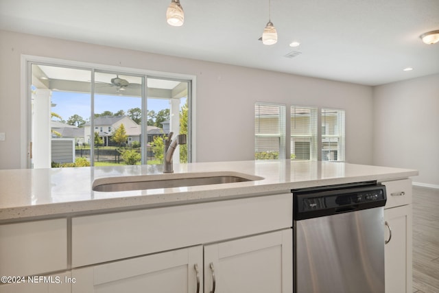 kitchen featuring pendant lighting, sink, light stone counters, white cabinets, and stainless steel dishwasher