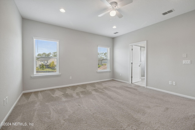 unfurnished room with light colored carpet and ceiling fan